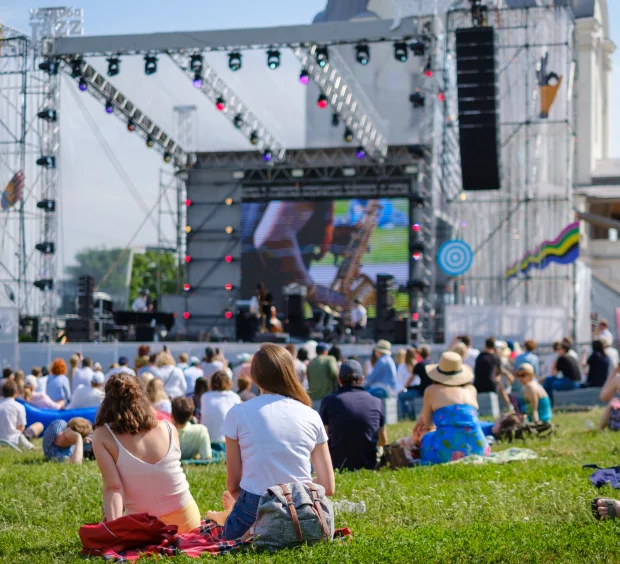 A group of individuals enjoying leisure time while seated on a grassy area, surrounded by nature.
