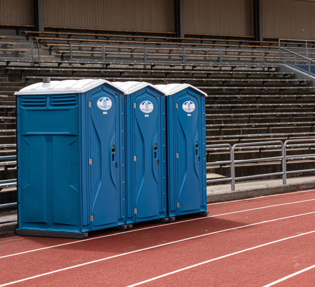 Portable toilets arranged in a line on a track, offering essential sanitation options for outdoor activities or sporting events.